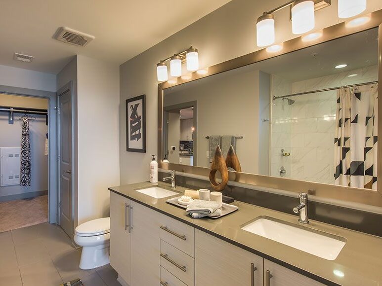 Apartment bathroom with porcelain tile shower backsplash and charcoal soapstone countertop vanity
