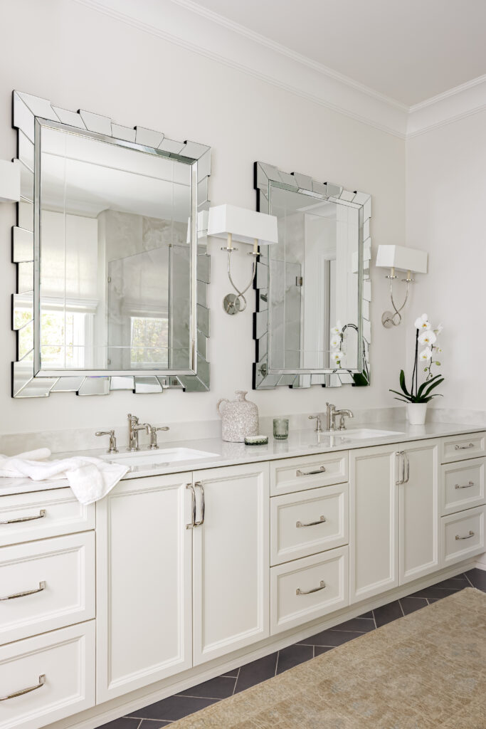 A bright white bathroom featuring two sinks and matching mirrors, creating a spacious and elegant atmosphere.