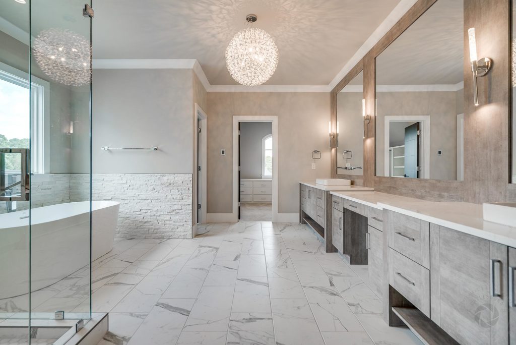 A spacious bathroom featuring elegant marble flooring and pristine white walls and countertops, creating a luxurious atmosphere.